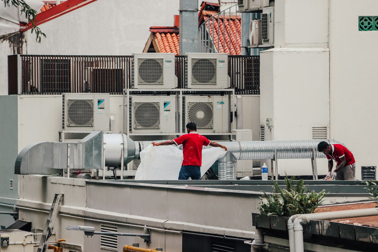 Two HVAC technicians collaborating on a rooftop unit
